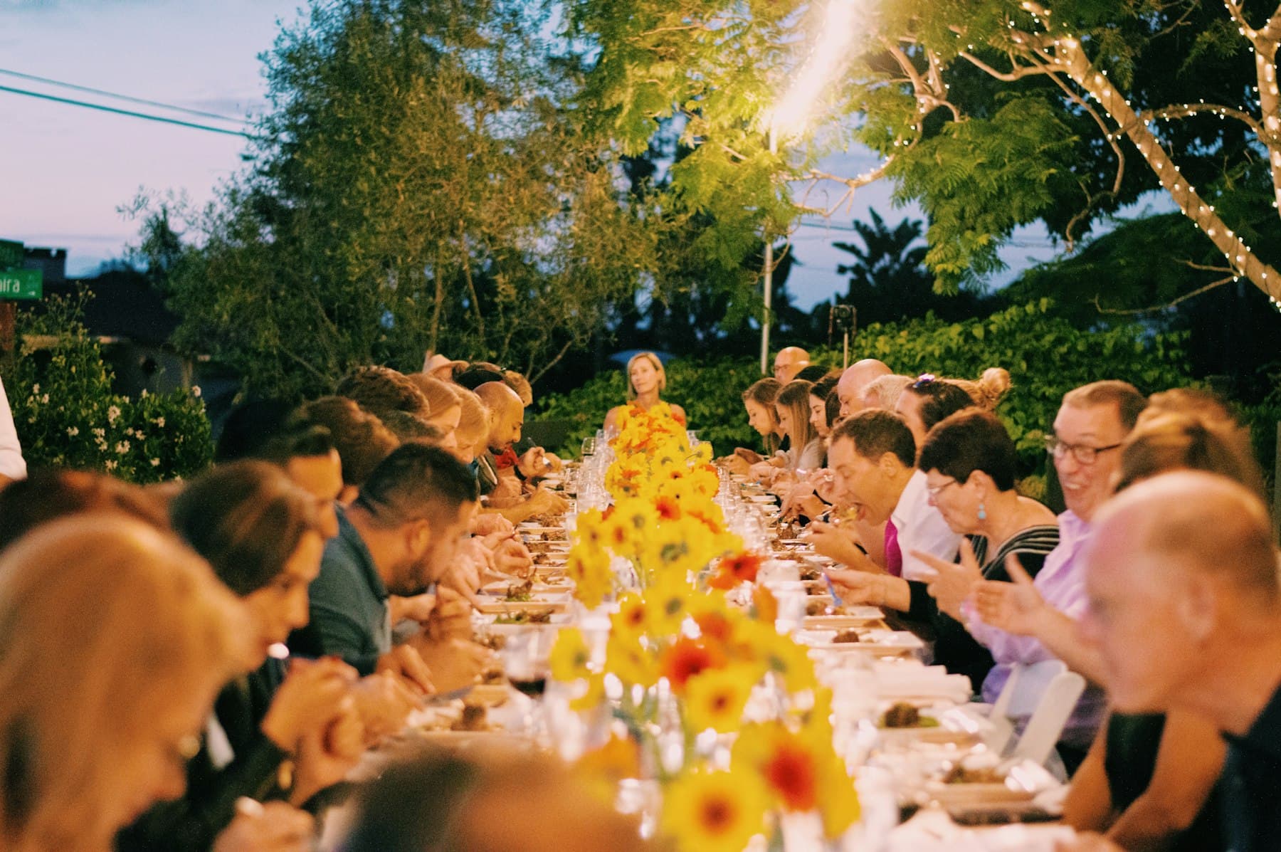 Guests gathered along a candlelit table under the trees