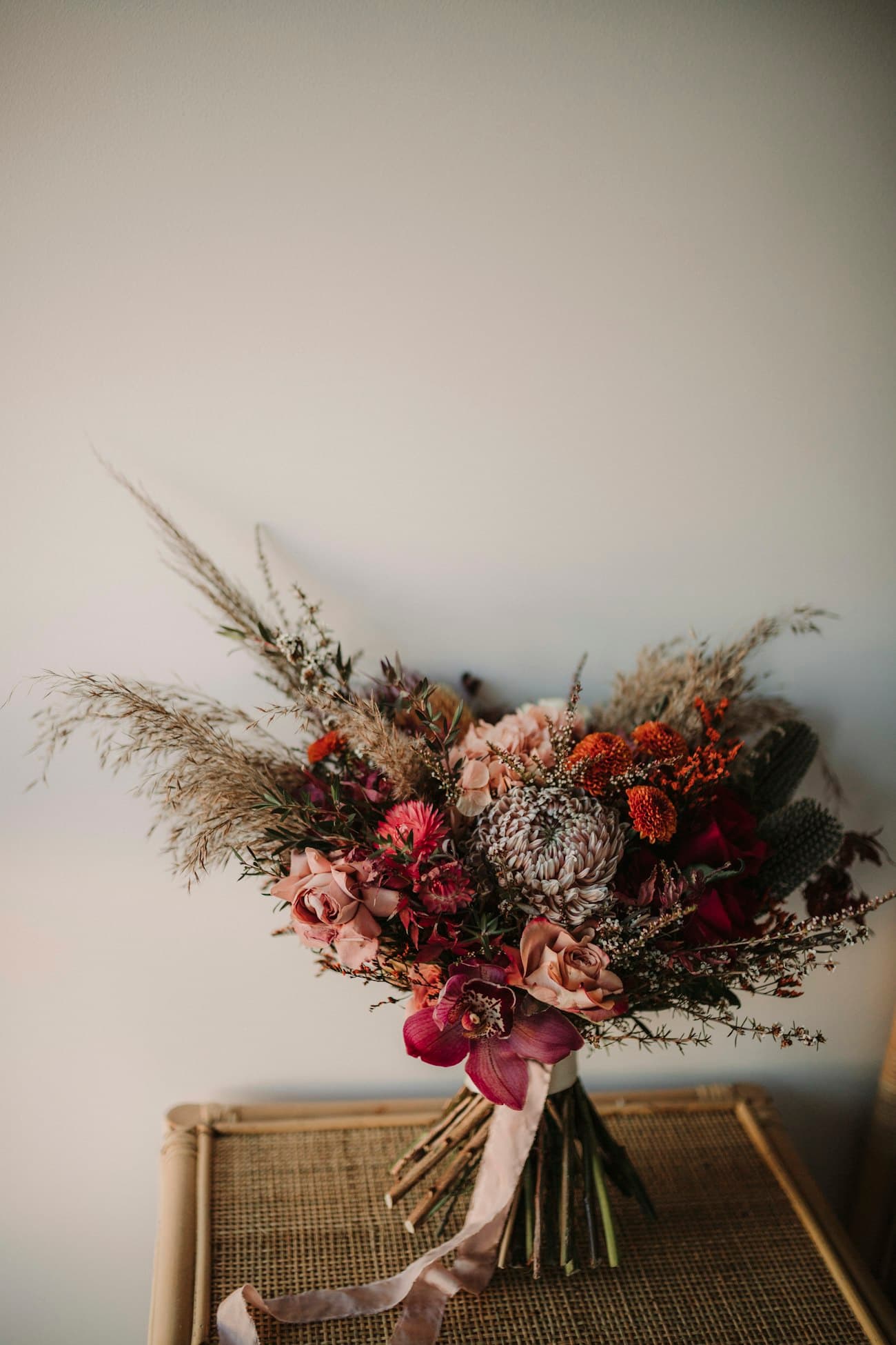 A dried-flower arrangement in terracotta, clay and sage