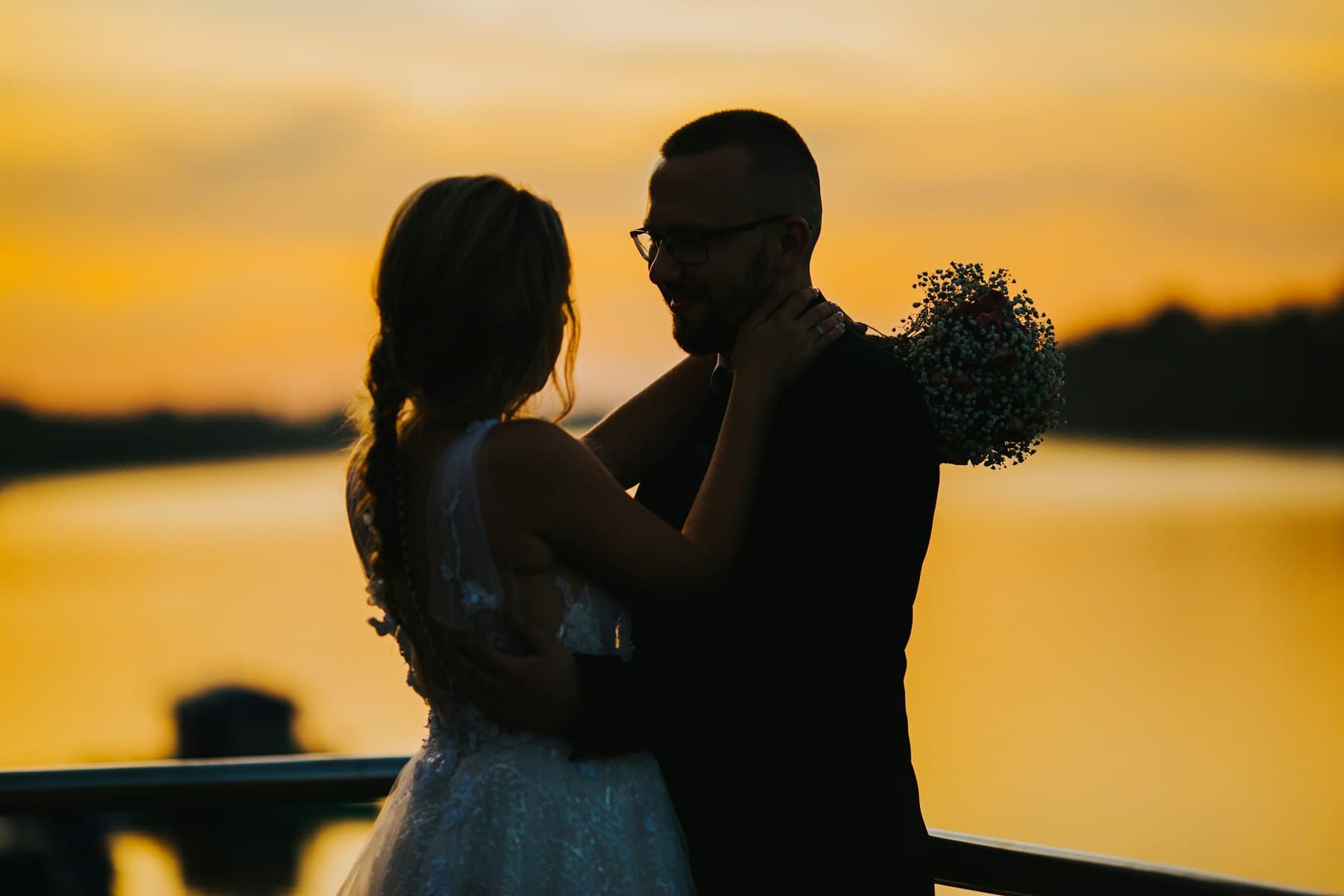 A couple silhouetted against a burnt-orange sunset