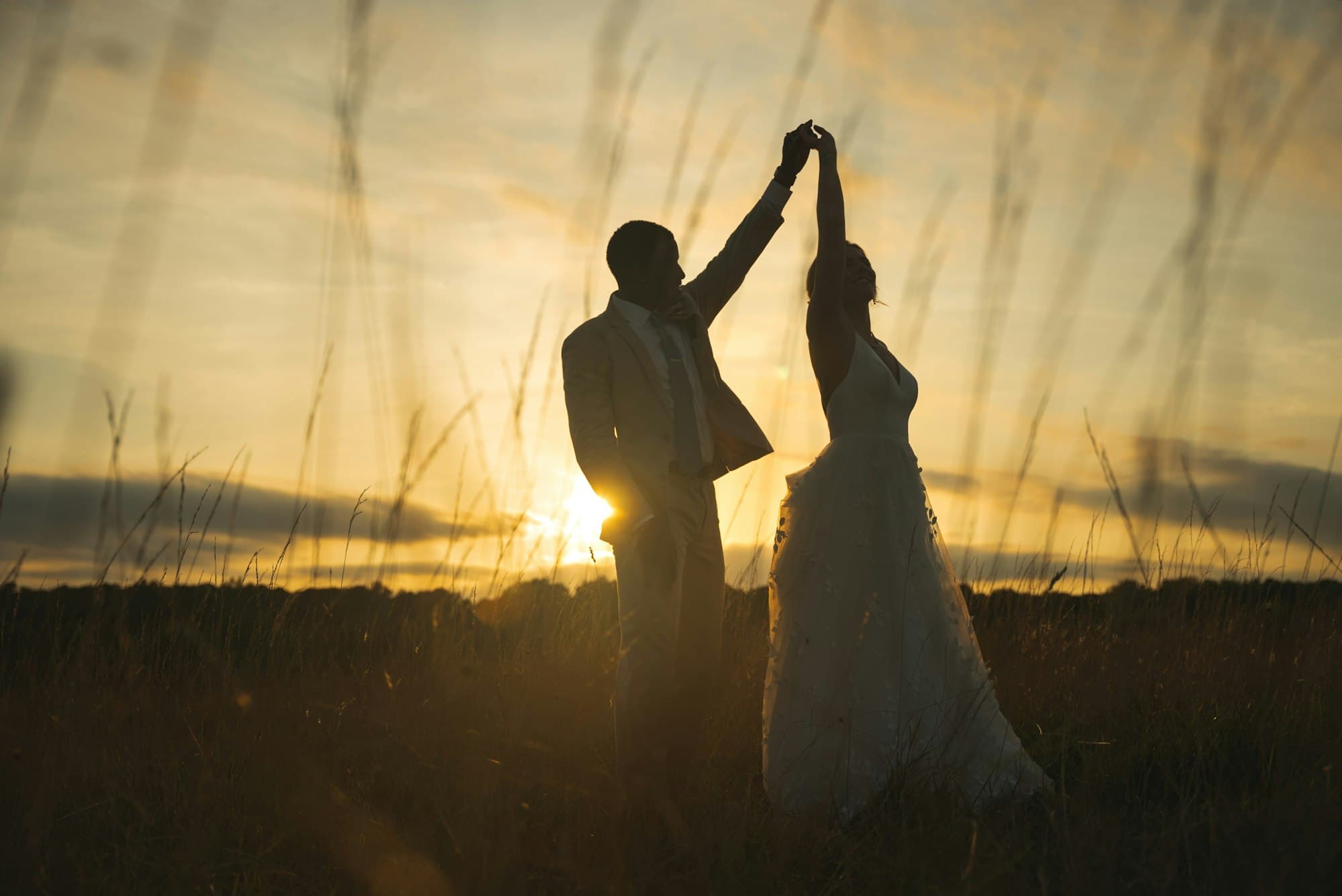 Maya and Daniel silhouetted against the sunset on the hillside